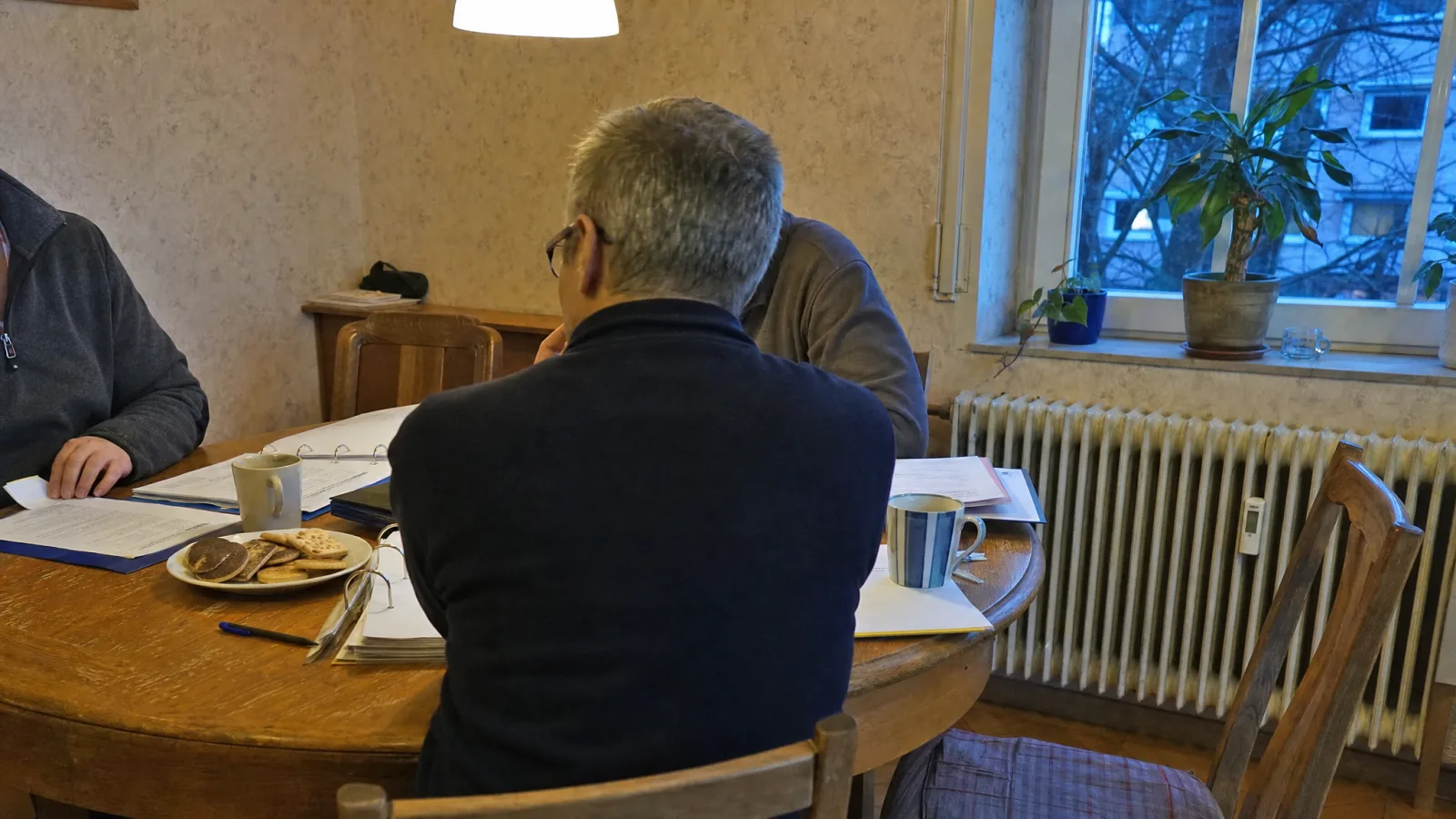 Beiratssitzung am Esstisch eines Eigentümers mit Ordnern und Kaffeetassen