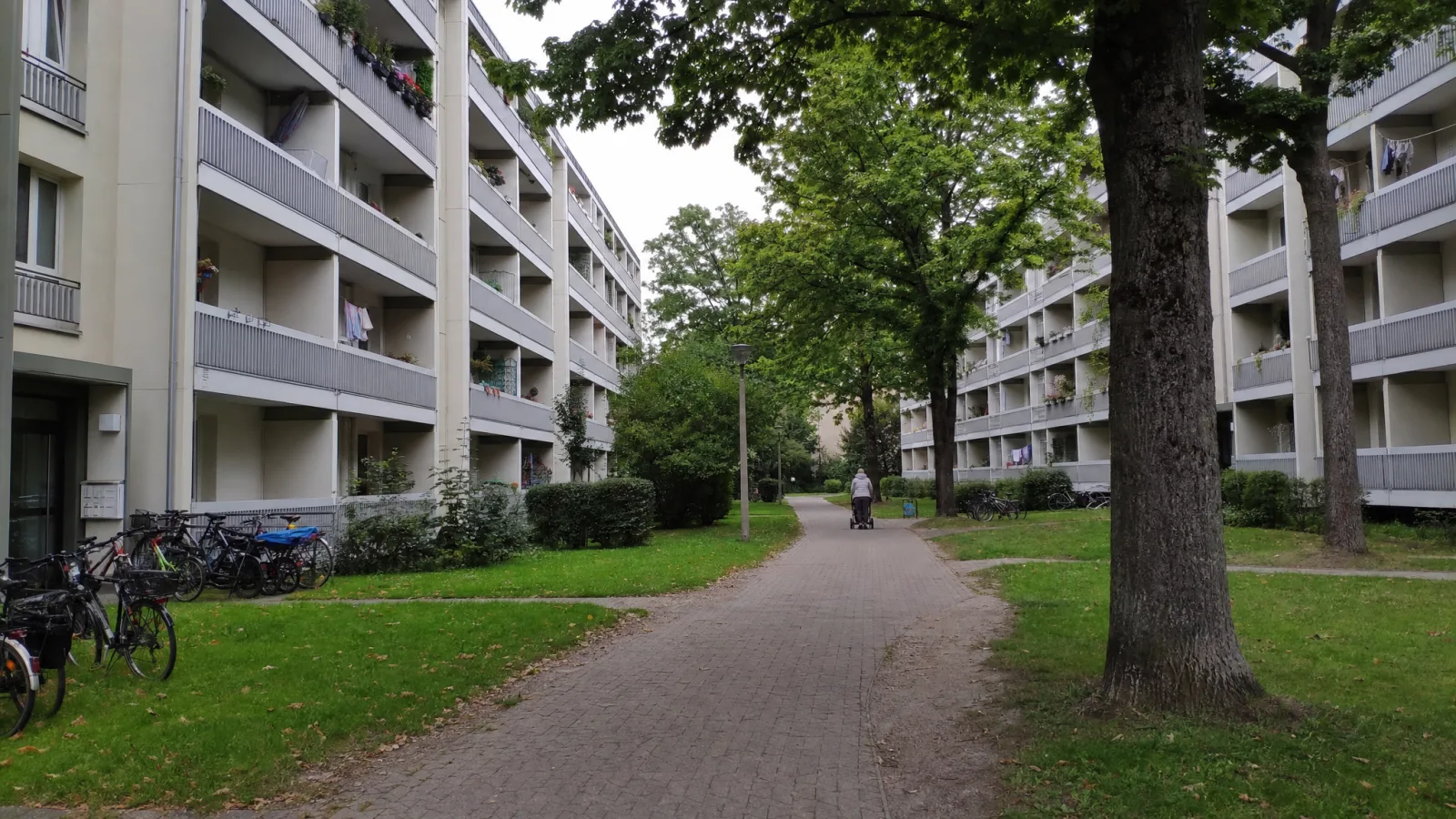 Innenhof einer großen, sanierten Wohnanlage mit Balkonen und Bäumen