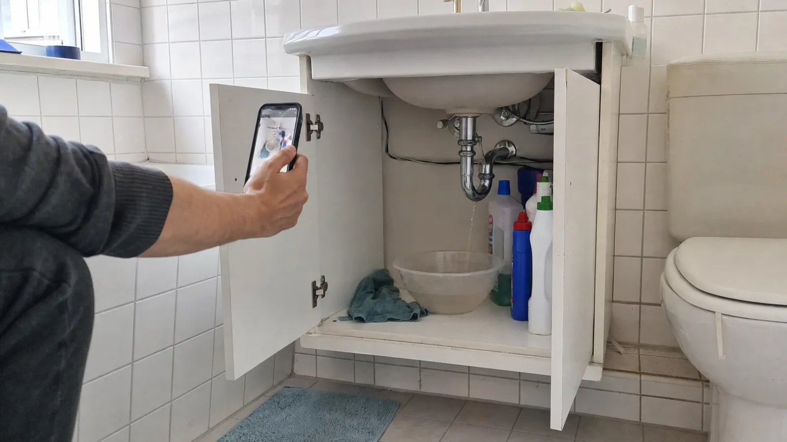 Tropfender Siphon unter einem Waschbecken, darunter eine Schüssel