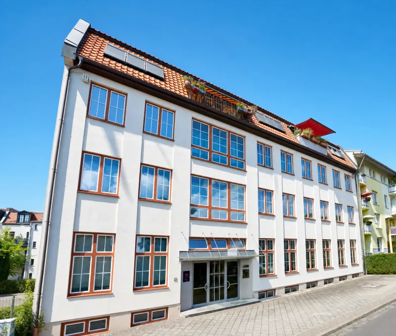 Modernes Mehrfamilienhaus mit grauer Fassade und rotem Ziegeldach